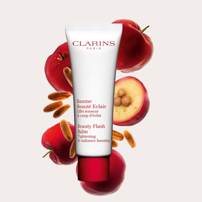 Kuva Clarins Beauty Flash Balm tuubi ja acerolakirsikoita persikanv&auml;rist&auml; taustaa vasten.