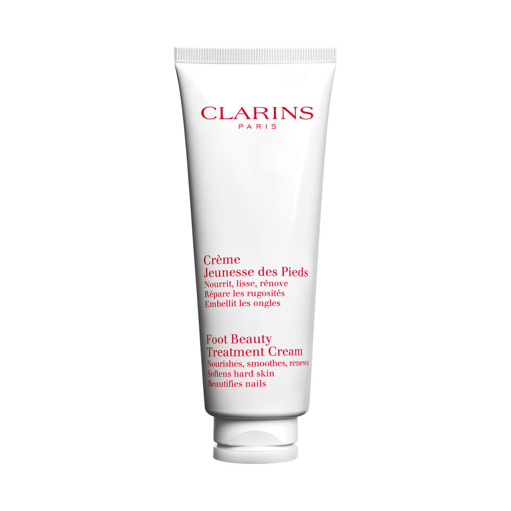 Kuva Clarins Clarins Foot Beauty Treatment Cream tuubista ja karitepuun p&auml;hkin&ouml;ist&auml; valkoista taustaa vasten.