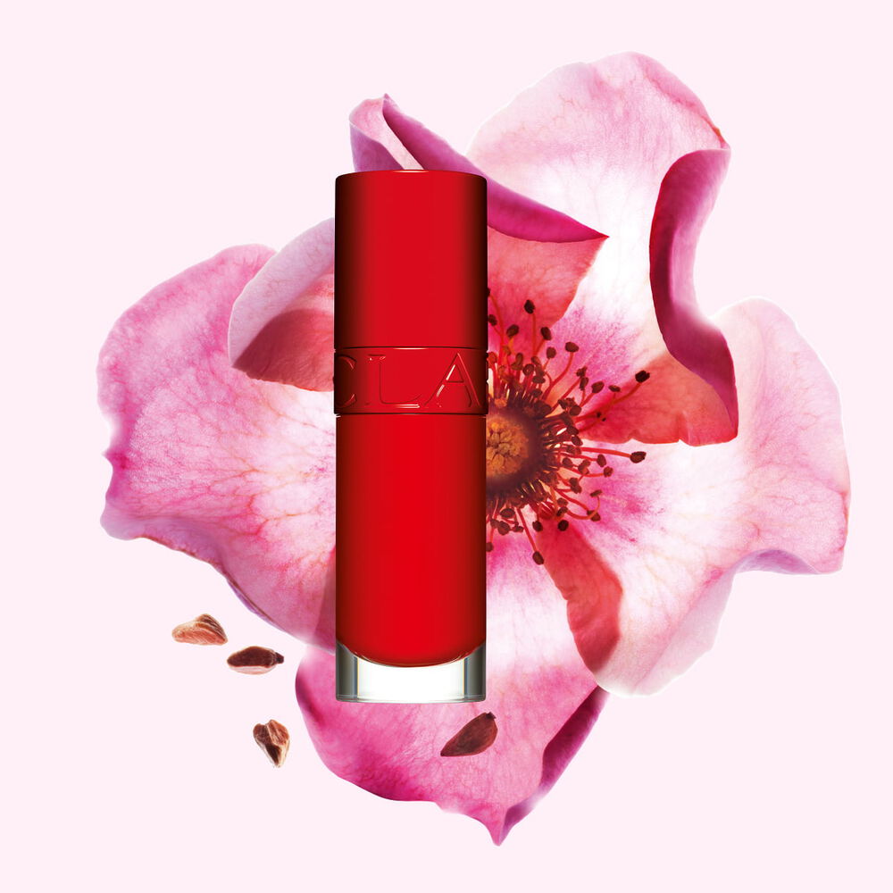 Packshot Clarins Lip Comfort Oil -tuotteesta Iconic Red -s&auml;vyss&auml;,  ruusumarjakukka musta-punaisella taustalla.