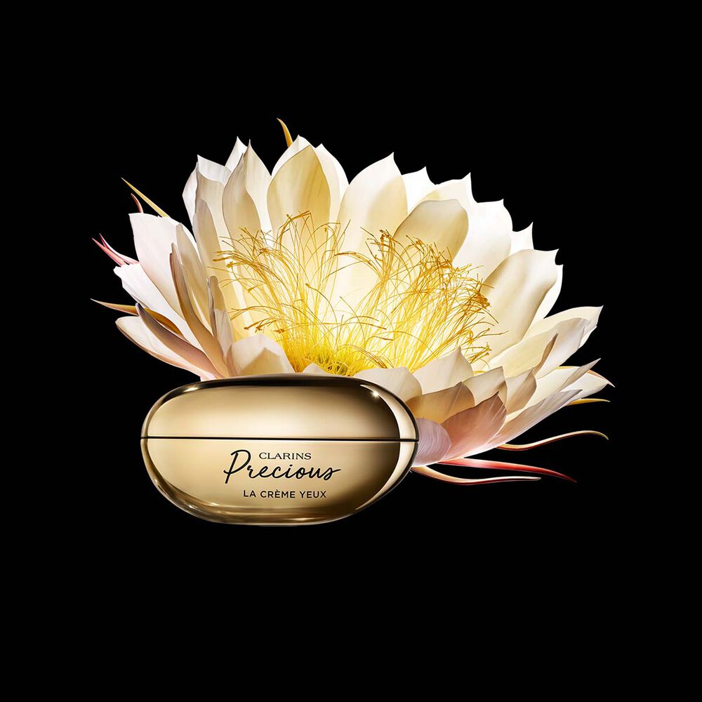 Kuva Clarins Precious Eyes silmänympärysvoiteesta ja yökaktuksen kukasta tummaa taustaa vasten.