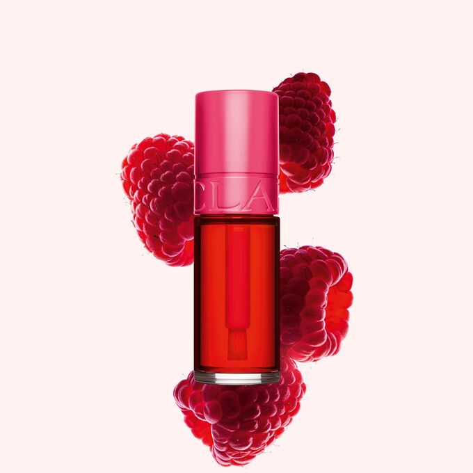 Packshot Clarins Fushia Water Lip Stain -huuliv&auml;rist&auml; s&auml;vyss&auml; 01, asetettuna vadelmien viereen vaaleanpunaiselle taustalle.