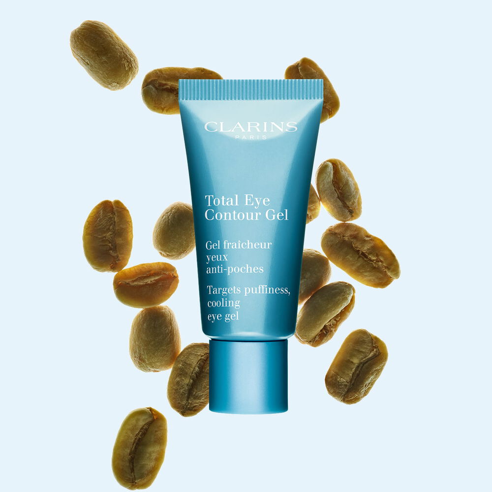 Kuva Clarins Total Eye Contour Gel tuubista ja kahvipavuista sinist&auml; taustaa vasten.