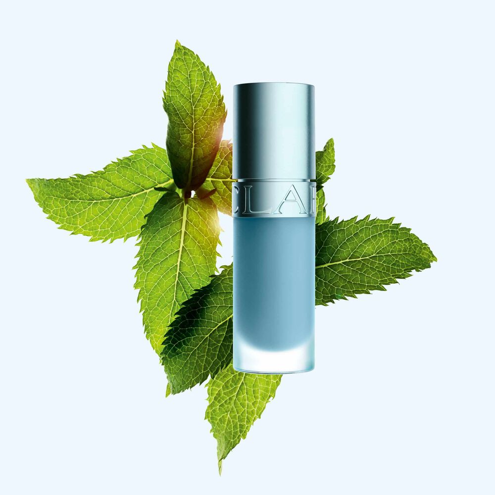 Clarins Lip Comfort Oil -huuli&ouml;ljyn tuotekuva uudella viilent&auml;v&auml;ll&auml; vaikutuksella ja kiilt&auml;v&auml;ll&auml; lopputuloksella, sijoitettuna mintun eteen korostamaan sen keskeist&auml; ainesosaa