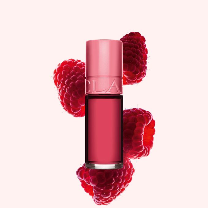 Packshot Clarins Pink Water Lip Stain -huuliväristä sävyssä 11, asetettuna vadelmien viereen vaaleanpunaiselle taustalle.