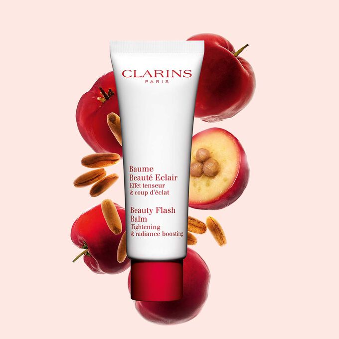 Kuva Clarins Beauty Flash Balm tuubi ja acerolakirsikoita persikanväristä taustaa vasten.