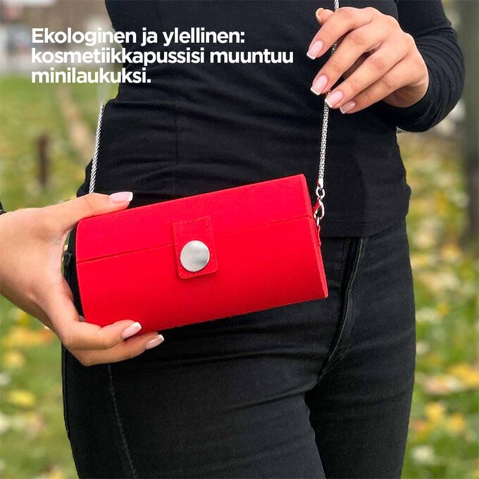 Lähikuva kosmetiikkapussista, joka näyttää sen punaisen muotoilun ja kyvyn muuttua minilaukuksi, jossa on hihna.